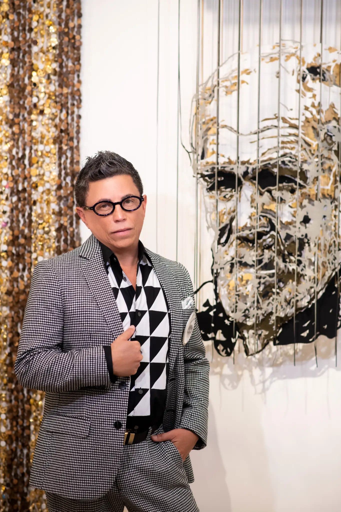 Aldo Castillo at the gallery, standing before a large portrait work