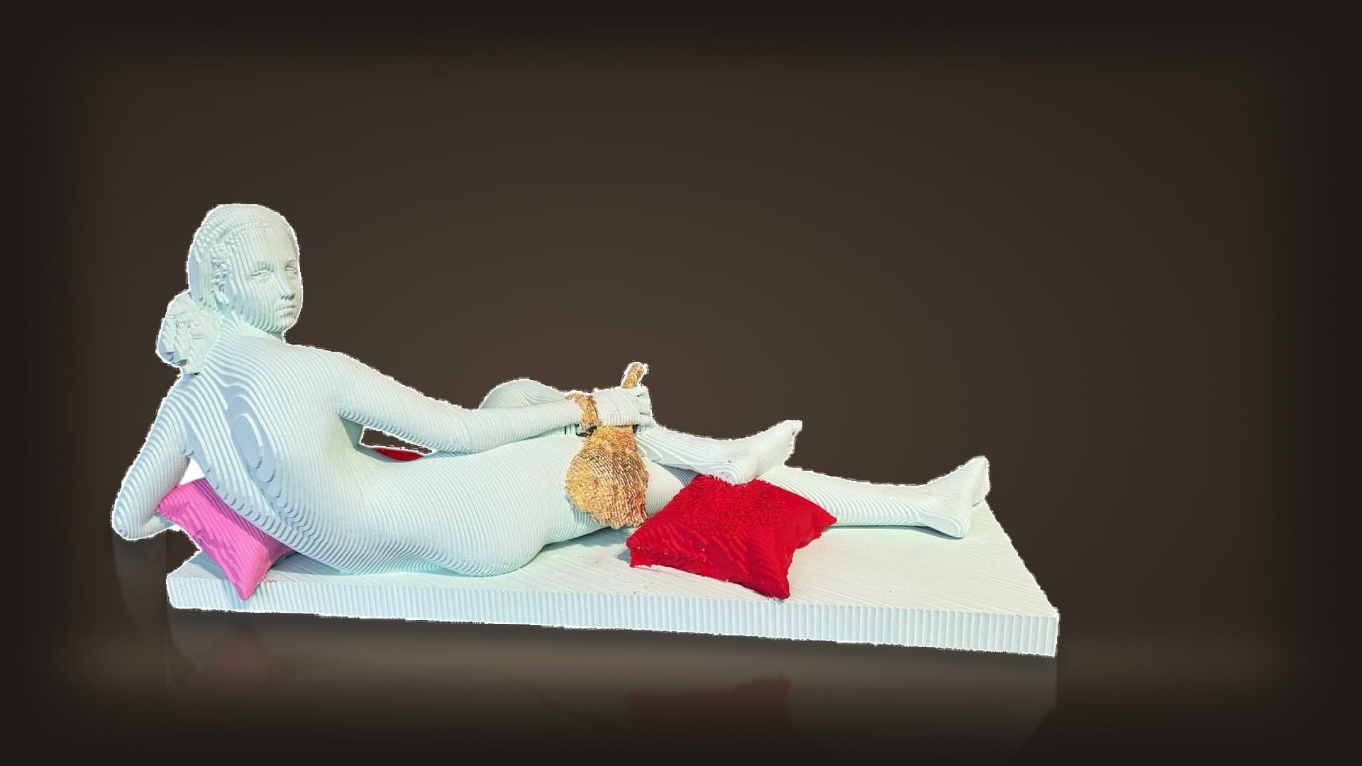 Daniele Fortuna, La Grande Odalisque: a pale layered wooden nude reclining on a slab, with red and pink cushions and a gilded fan