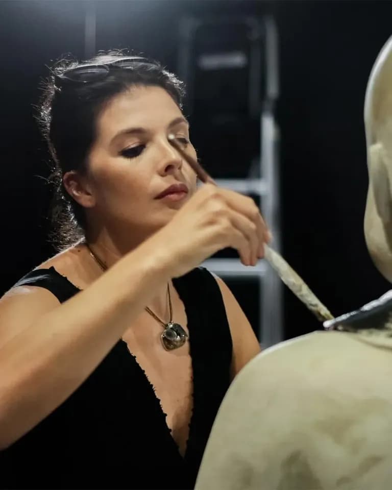 Metis Atash in the studio, raising a fine brush to a bare cast.