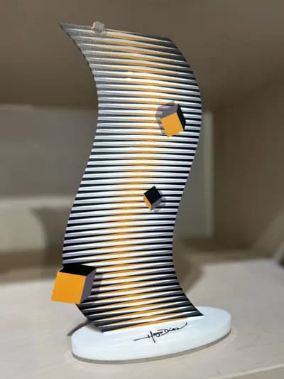 A curved plexiglass sculpture by Hugo Diaz in black and gold stripes, with coloured cubes on its face