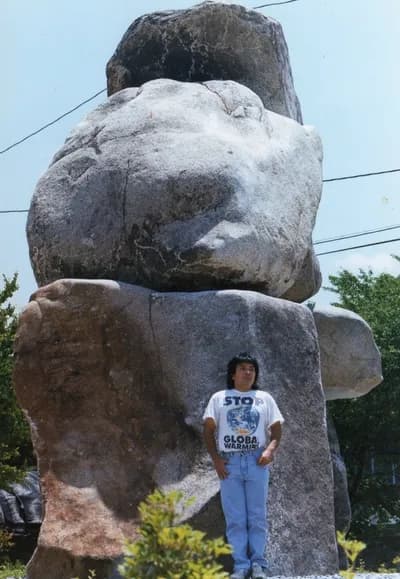 A large stone monument by Kennsuke Sasaki outdoors, with a person standing beside it for scale