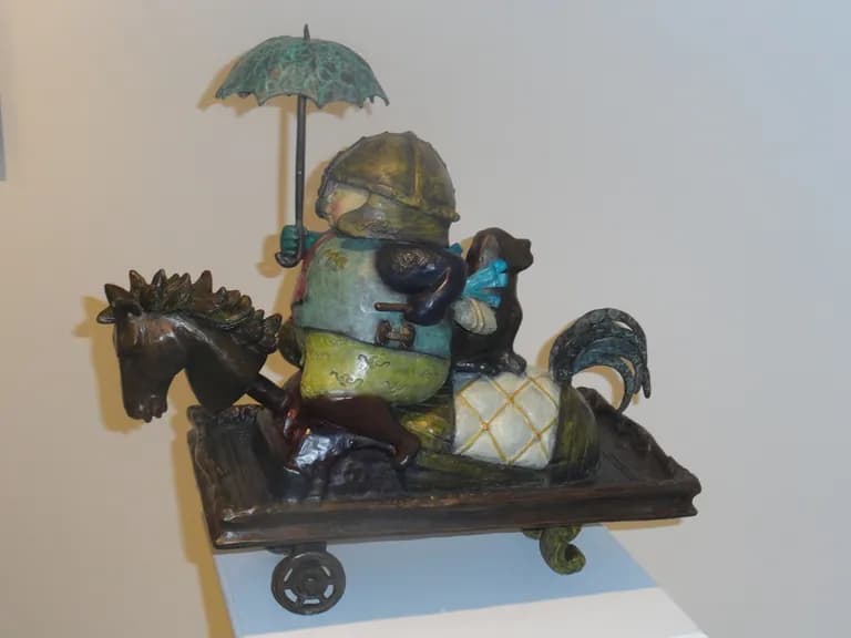 A ceramic figure under an umbrella riding a wheeled horse, by Rodo Padilla