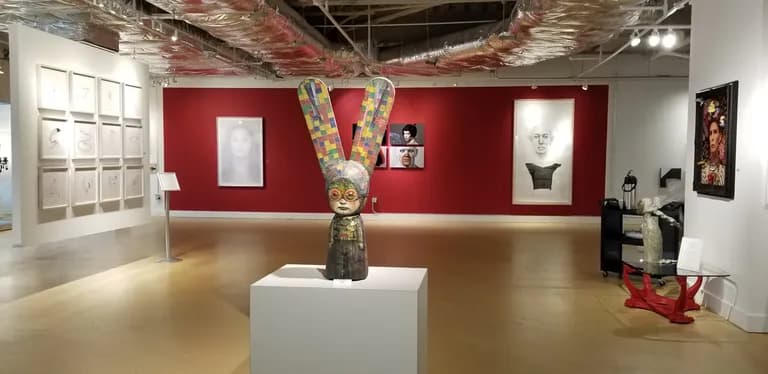 A figure by Mariana Monteagudo lit on a plinth in a dark gallery