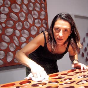 Carolina Sardi at work on a red perforated steel panel