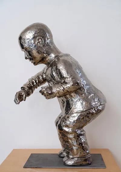 A glazed ceramic figure by Patricia Rieger, standing with an arm raised