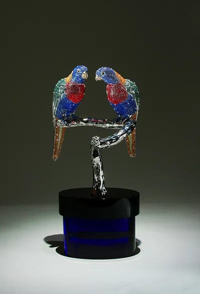Two crystal encrusted parrots by Clarita Brinkerhoff on a stand