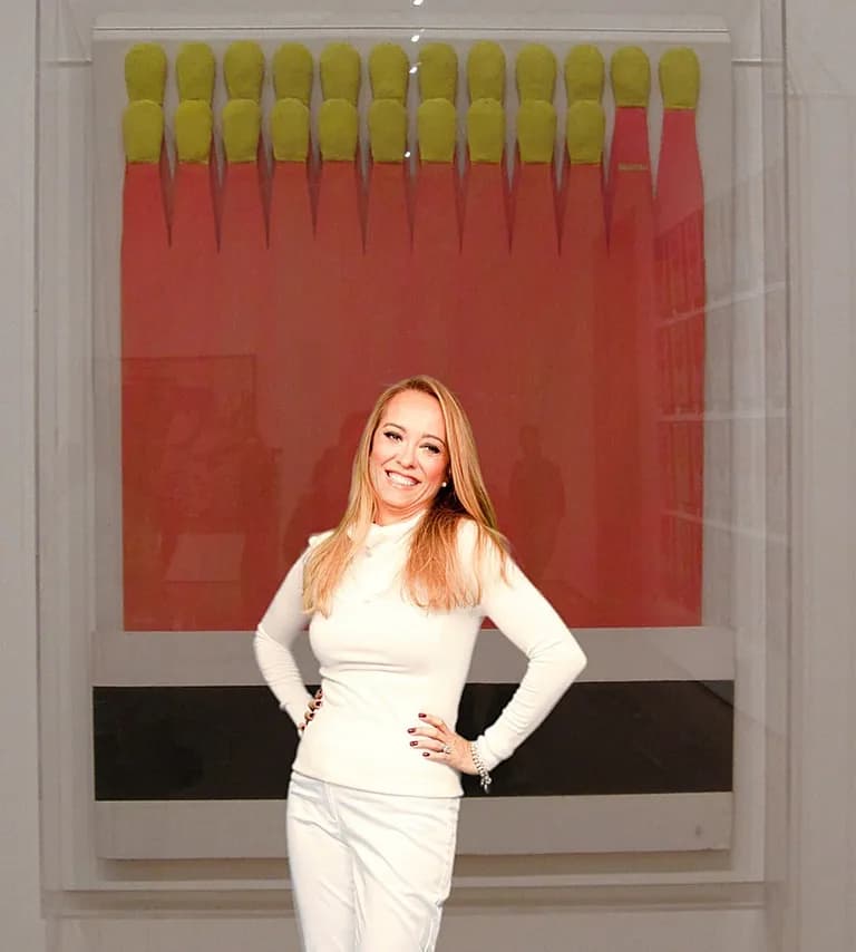 A woman in a white dress standing in front of a large red work