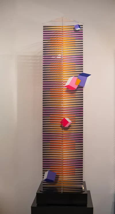 A tall plexiglass tower by Hugo Diaz striped in orange, with coloured cubes fixed to its face