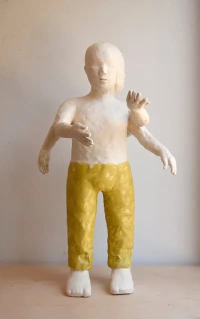 A glazed ceramic figure by Patricia Rieger in yellow trousers