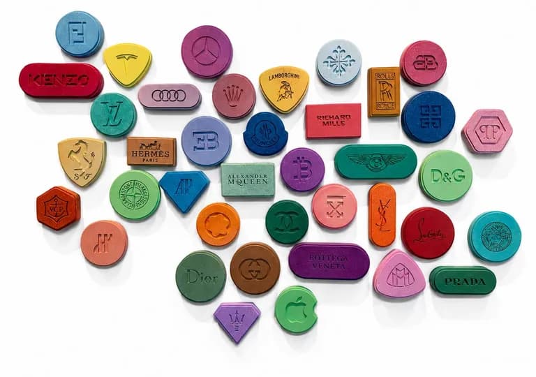 A wall of carved and painted wooden pills bearing brand marks, the full installation of ADDICTED by Kevin Langedijk