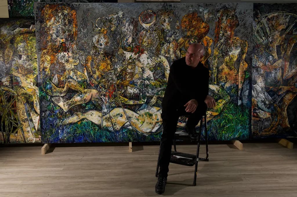 Fredy Villamil seated in front of his painting Muse