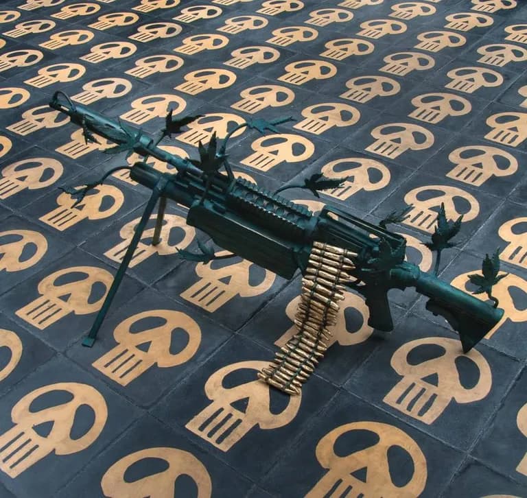 A bronze machine gun by Emiliano Gironella Parra against a ground printed with skulls