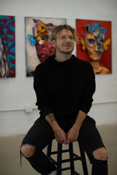 Tomaso Albertini seated in front of two of his paintings